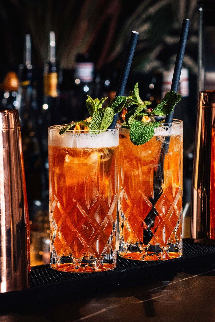 Zwei Longdrinks mit frischer Minze im Tiger Room Würzburg vor Flaschenregal